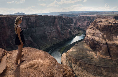 Side view of woman standing on cliff against horseshoe bend