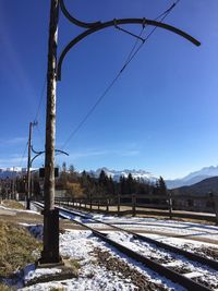 Railroad tracks by snowcapped mountains against clear blue sky