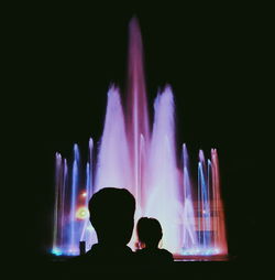 Silhouette man and woman against illuminated fountain