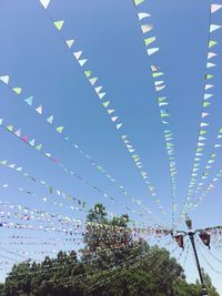 Low angle view of buntings hanging against blue sky