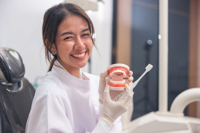 Portrait of young woman holding dentures