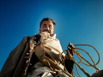 Low angle view of man sculpture against blue sky