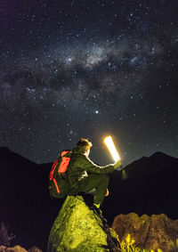 Young man sitting on a stone in the andes mountains observing the gala