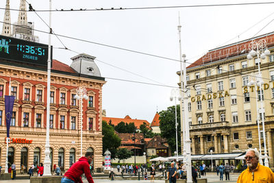 People on street against buildings in city