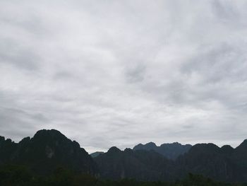 Low angle view of trees against cloudy sky