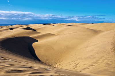 Sand dunes at beach against sky