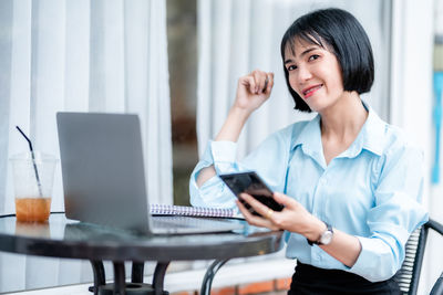 Young woman using mobile phone at table