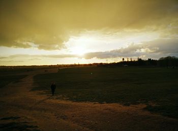 Silhouette man on beach against sky during sunset