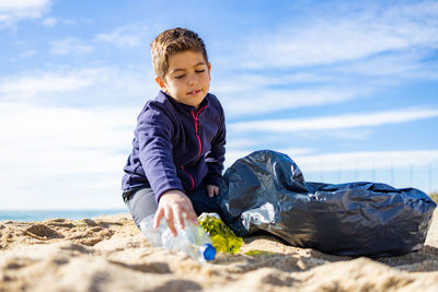 Little kid picking plastic on the beach. recycling concept