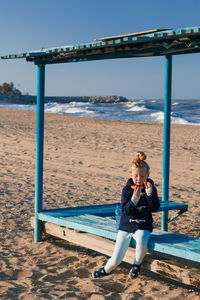 Full length portrait of young woman sitting on beach