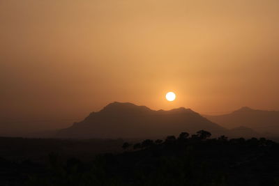 Scenic view of silhouette mountains against orange sky