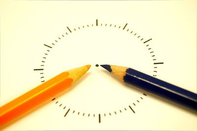 Close-up of clock made with colored pencils on white paper