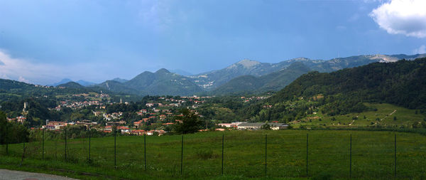 Scenic view of field by mountains against sky