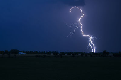 Lightning over silhouette landscape against blue sky