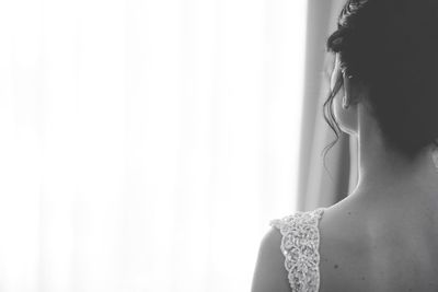 Close-up rear view of bride looking through window