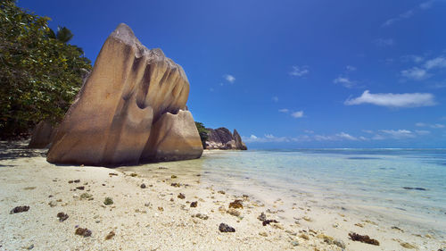 Scenic view of rocks on beach against blue sky