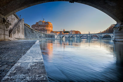 Arch bridge over river against buildings