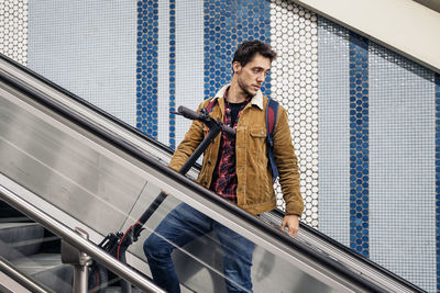 Man in stylish outfit with electric scooter in the mechanic stair of underground