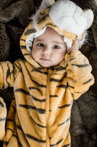 High angle portrait of cute baby girl wearing costume lying on blanket at home
