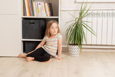 Child sits on the floor in the room near the bookcase. leisure and education at home. 