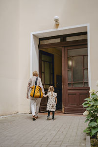 Rear view of grandmother and granddaughter entering in building