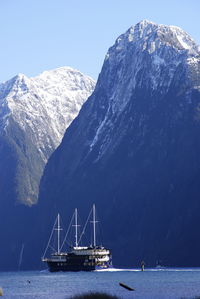 Sailboat on sea by snowcapped mountains against sky