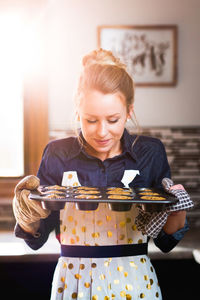 Smiling woman holding cookies in tray