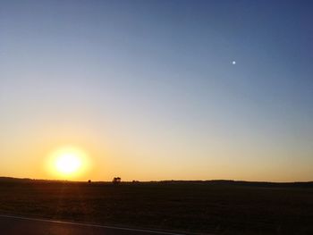 Scenic view of field against clear sky during sunset