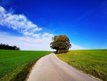 Road amidst field against sky