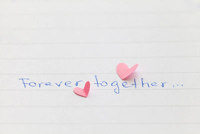 Close-up of forever together text by heart shape on paper