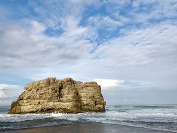 Rock formation on beach against sky