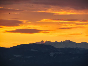 Scenic view of silhouette mountains against orange sky