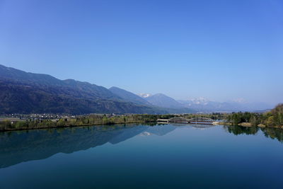 Scenic view of lake and mountains against clear blue sky