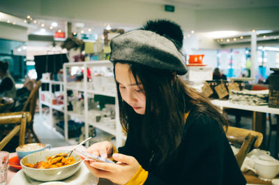 Woman using phone while having food in restaurant