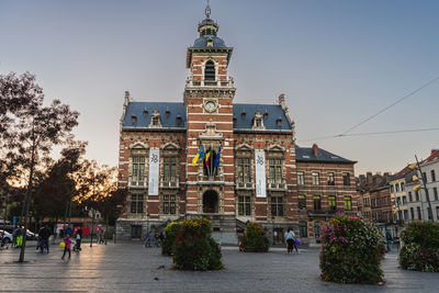 Twon hall of anderlecht at sunset. families and people enjoying the sunset at town hall square