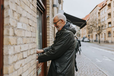 Side view of senior male entrepreneur closing door of antique shop while standing on footpath