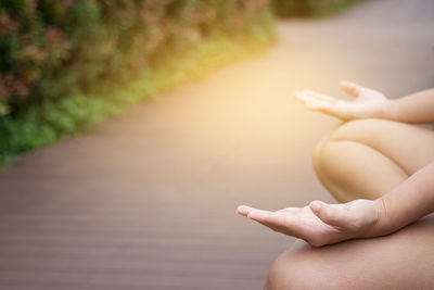 Cropped image of woman doing yoga on road