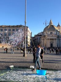 Group of people in front of building against clear blue sky