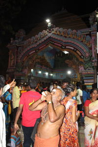 Rear view of people standing at illuminated temple at night