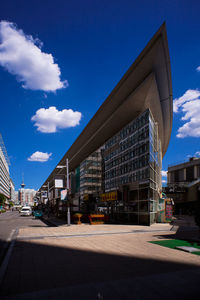 Road by buildings against blue sky in city