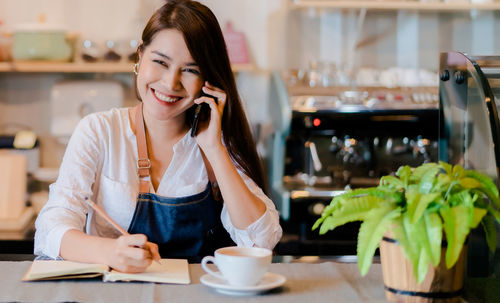 Young woman using mobile phone while sitting on table