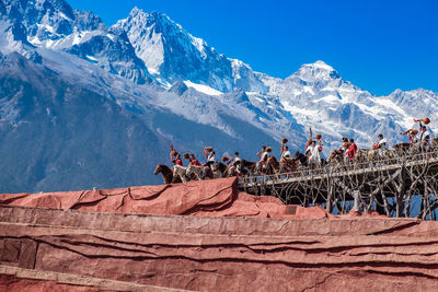 People on snowcapped mountain against sky