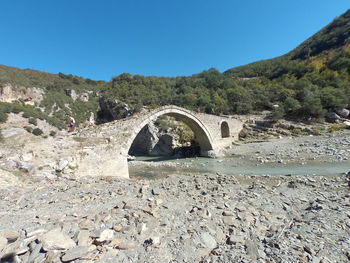 Arch bridge over land against clear blue sky