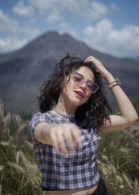 Beautiful young woman with arms raised standing on field