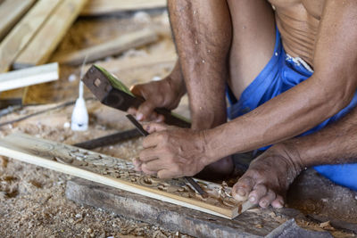 Midsection of man carving wood