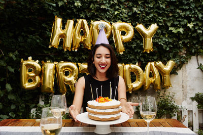 Smiling woman celebrating birthday against balloons