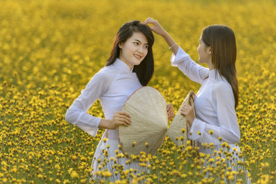 Women standing on field with yellow flowers in background