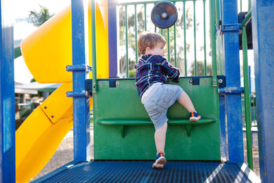 Modern colorful kids playground. outdoor plastic playing area for children. little boy on swing