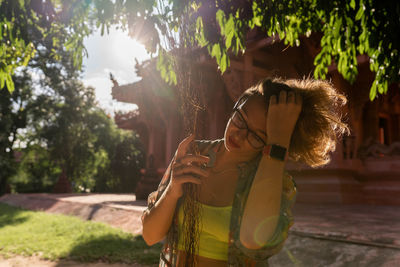 Side view of woman looking away while standing against trees