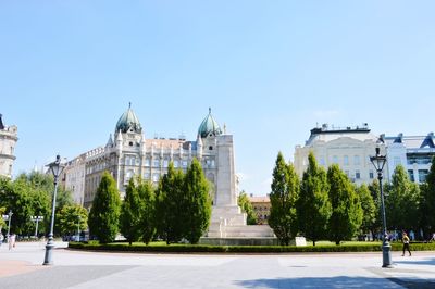 Trees and buildings against clear sky
